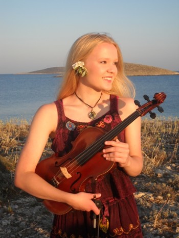 Celka holding a violin at a beach